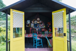 Sophie Robinson interior designed this she shed to be a creative work space where she could do ctaft projects, diy and upcycling. The dark walls work brilliantly with the opos of colour