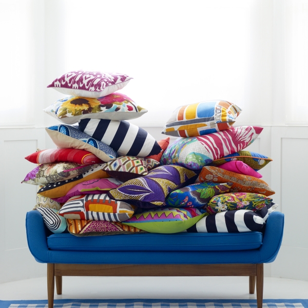 Blue sofa with a pile of pattern clash fabric cushions. Image styled by Mary Norden