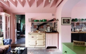 Pale pink kitchen with green le cruset pots and a cream aga. From the home of Solage Azagury Partridge