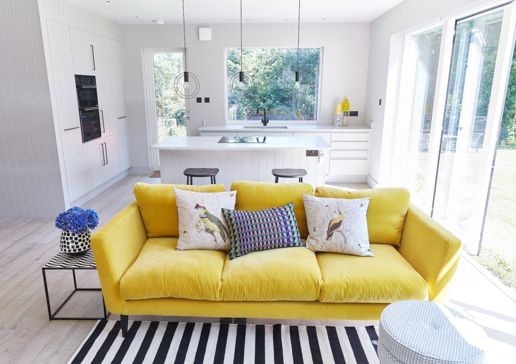 a canary yellow velvet sofa adds a pop of colour to an all great interior. The open plan living room kitchen is at the home of interior designer Sophie Robinson