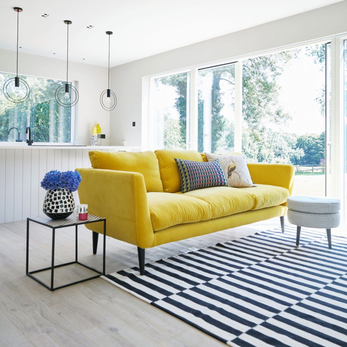 Canaray yellow velvet sofa adds a pop of colour to an all grey living room in the new annex build at the home of interior deisgner Sophie Robinson