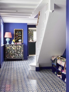 Colour queen Sophie Robinson reveals her renovated hallway featuring vibrant blue walls painted in Zoffany's Lazuli and a unique black sideboard with multi-coloured floral design, #sophierobinson #hallway #shoestorage #claybrook #patternedfloor