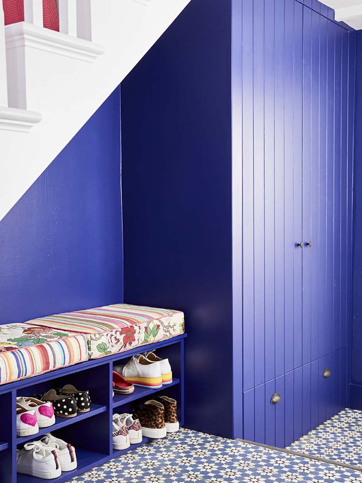 Interior designer Sophie Robinson has re-designed and renovated her hallway into and bright and welcoming space with under-stair show storage and cupboard all painted the same colour as the walls