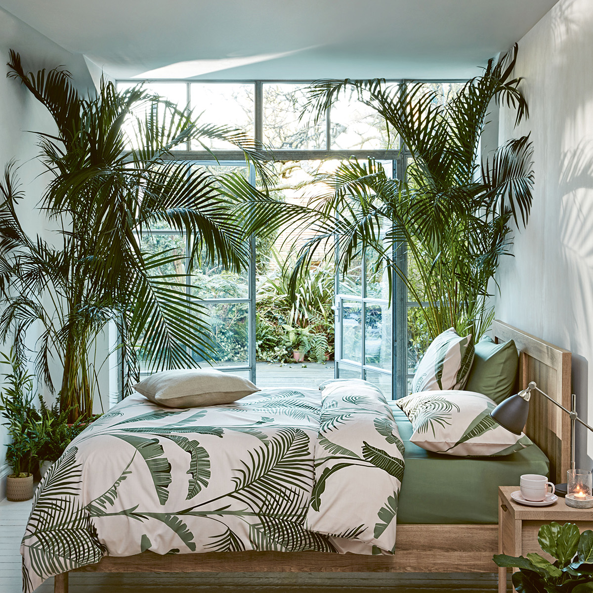 Looking at the soft tropics trend, Sophie Robinson advises to invite nature inside with living plants and go for it in volume to create a really dramatic lush look. A large palm print bedlinen can add to the drama. #bedroom #palmprint #sophierobinson #softropics
