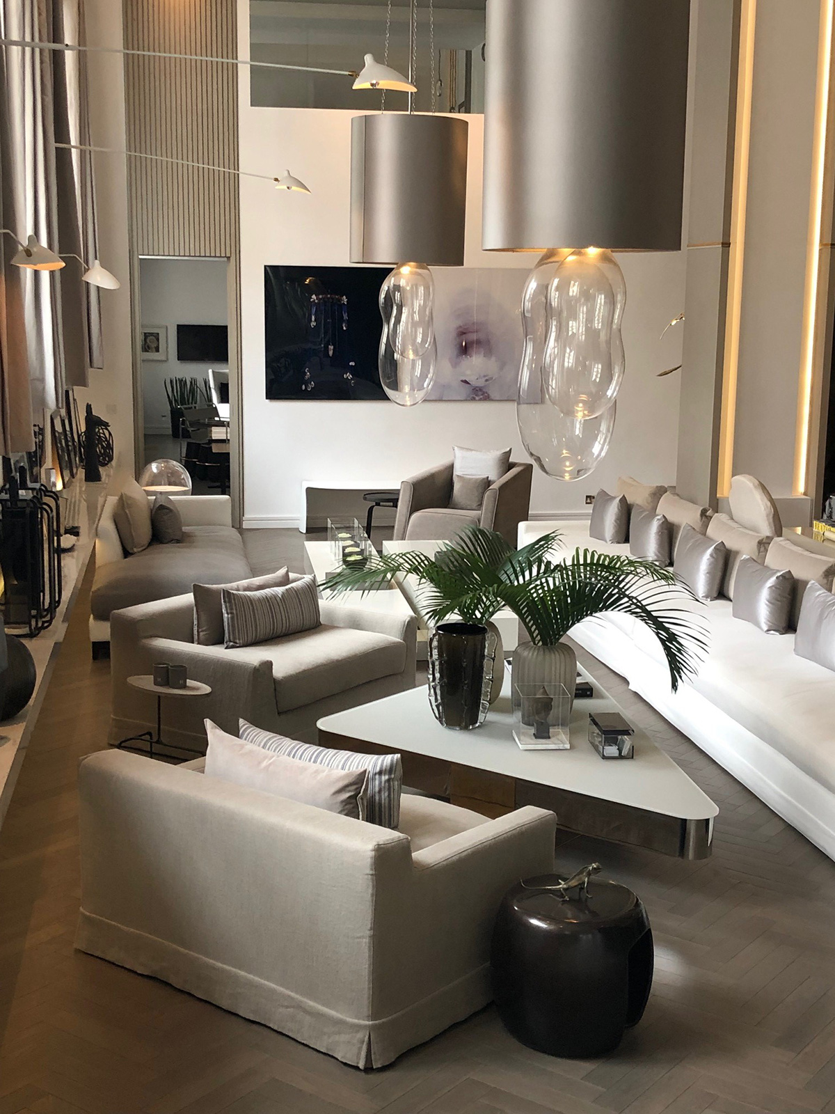 The open plan living room of interior designer Kelly hoppen includes large statement lighting and furniture in her signature taupe colour palette. Hear about the entire house tour on The Great Indoors Podcast. #kellyhoppen #openplan #sophierobinson