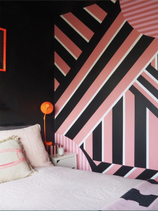 Sophie Robinson and Kate Watson-Smith chat about maximalism vs minimalism among other interior topics on the Great Indoors podcast. Quirk & Rescue’s extra wide pink and black striped bedroom wall enhances the plain black wall and neutral textiles. #thegreatindoors #bedroom #stripedwallpaper #sophierobinson