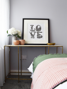 A soft palette of pale pink, green and grey creates a cosy and restful bedroom scheme, while the bold LOVE print adds a modern monochrome touch. Designed by Sophie Robinson for BBC One's makeover show DIYSOS. #diysos #bedroom #sophierobinson