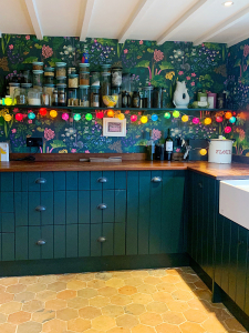 How to revamp on a budget as discussed on the Great Indoors podcast with Sophie Robinson and Kate Watson-Smyth. Sophie's kitchen was a bespoke design but on a budget with tongue and groove cabinet doors painted in a rich green - the perfect partner for the bold botanical wallpaper. #kitchen #sophierobinson #thegreatindoors