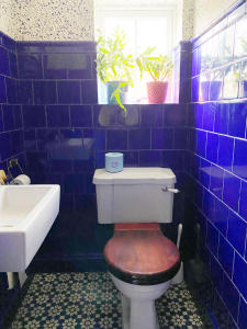 The downstairs wc in the home of Interior designer Sophie Robinson features rich cobalt blue wall tiles with dado rail and blue patterned floor tiles, finished off with a splatter design wallpaper. #bluetiles #bluebathroom #thegreatindoors