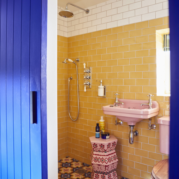 Shower room with yellow wall tiles, pink blue and yellow floor tiles and pink sanitaryware. In the home of Sophie Robinson
