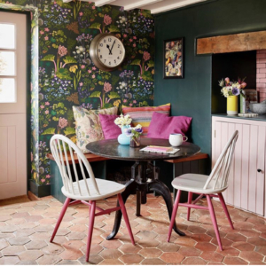 green and pink floral wallpaper, pink kitchen cabinet, round metal table with pink and white dining chairs
