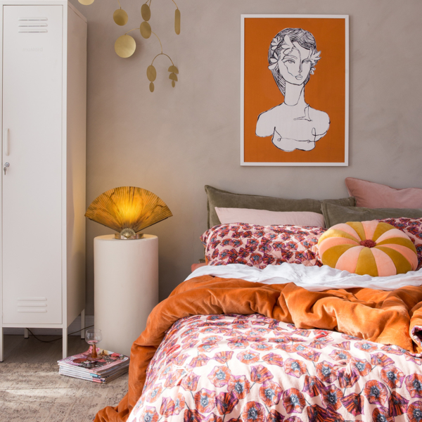 Bedroom with industrial style wardrobe, orange artwork and orange patterned bedding. From The New Mindful Home interior book by Joanna Thornhill