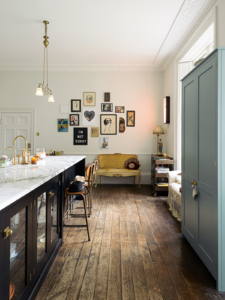 deVol kitchen in the home of Pearl Lowe, large central island with glass doors and marble top, small gallery wall and antique yellow upholstered bench