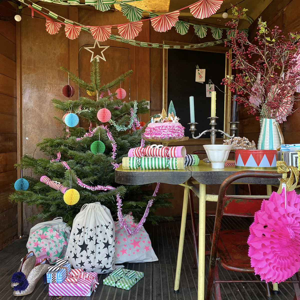 Colour Christmas with paper decoration on ceiling, small paper balls on the Christmas tree and star printed fabric gift bags by Petra Boase. Gift guide by Sophie Robinson
