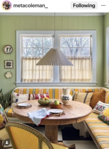 A fitted banquet seat in a small dining room breakfast booth in a bold yellow stripe fabric and green walls with a round dining table