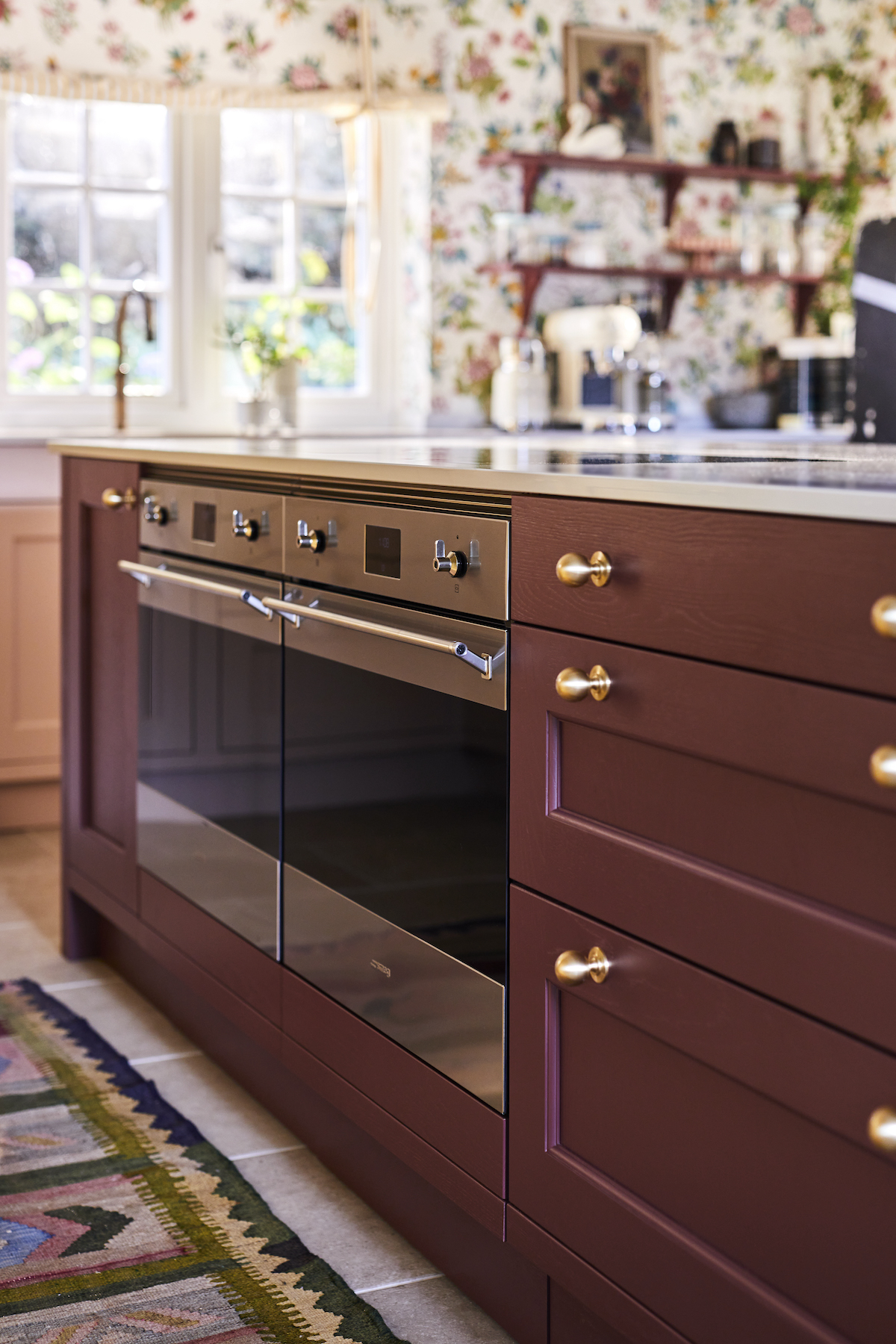 Close up of double oven in kitchen island with round brass handles on drawers next to it.