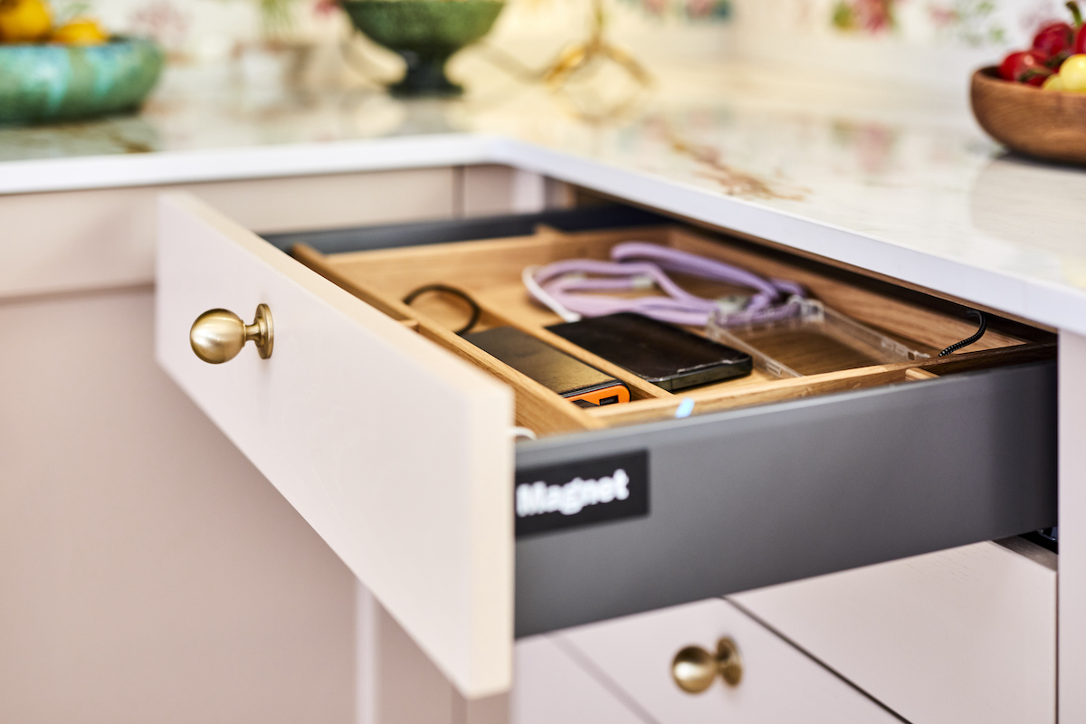 An open drawer with brass handle. Inside the drawer are multiple phones in a charging station. On the side of the drawer is a large Magnet logo.